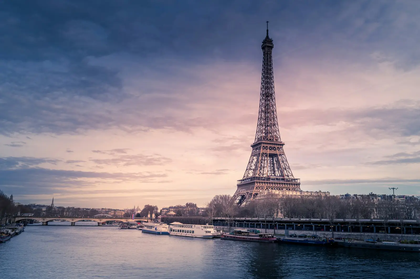 La Torre Eiffel sobre el Sena y sus barcos al atardecer