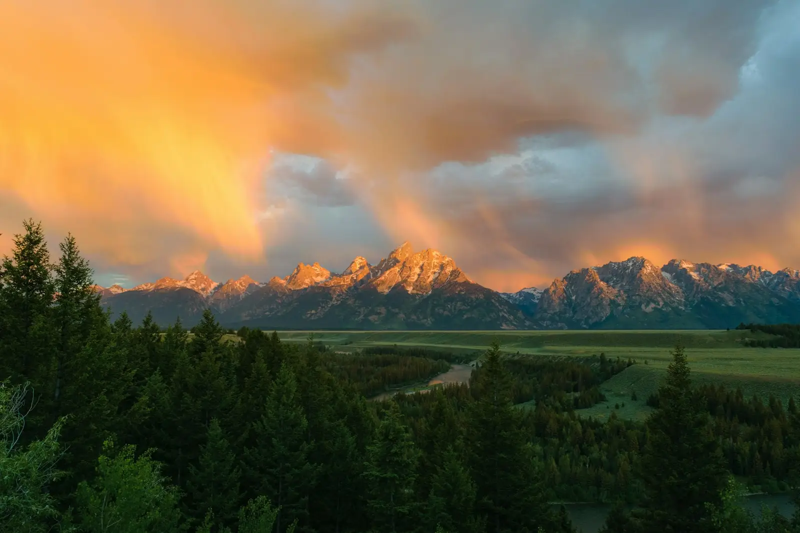 The Teton Range at sunrise above the Snake River and pine forest