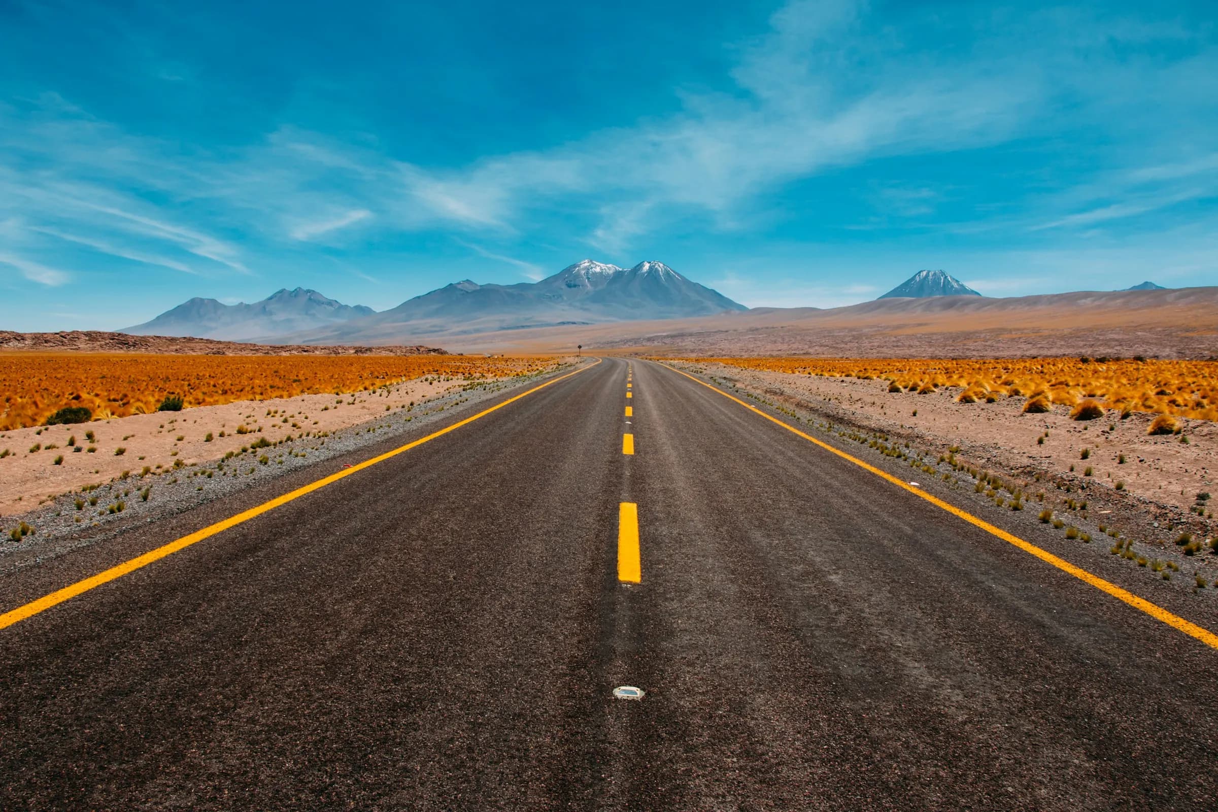 An empty road crossing the desert toward the mountains