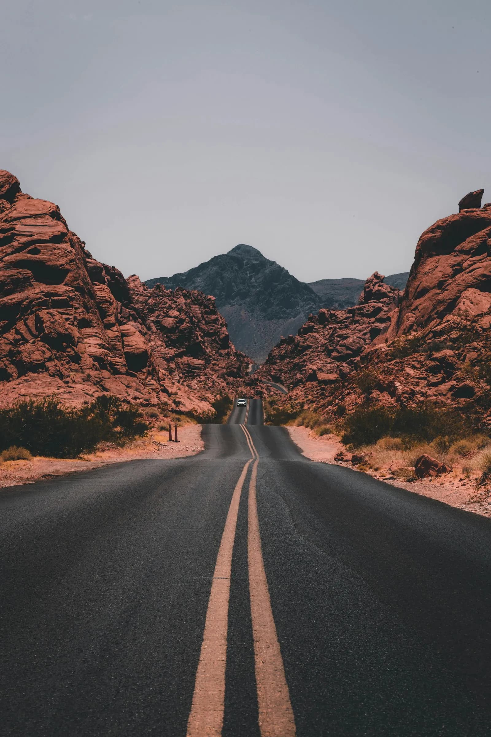 A straight road running through a red rock canyon toward a distant peak
